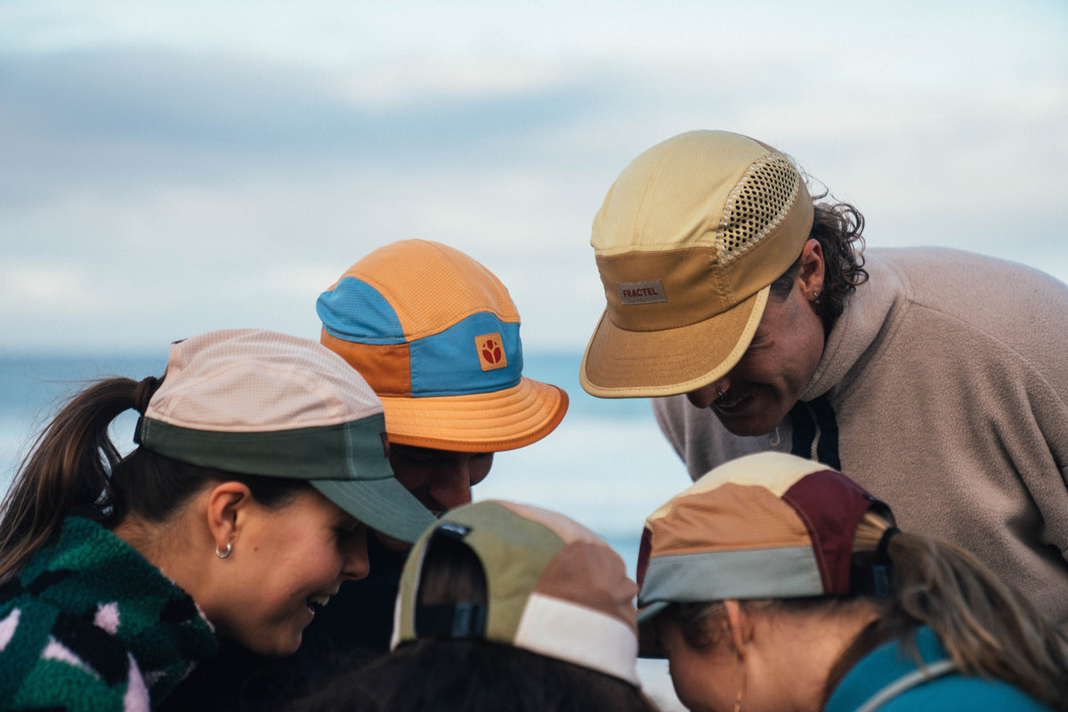 Group of runners comparing colourful Fractel caps from the Australian insect running collection