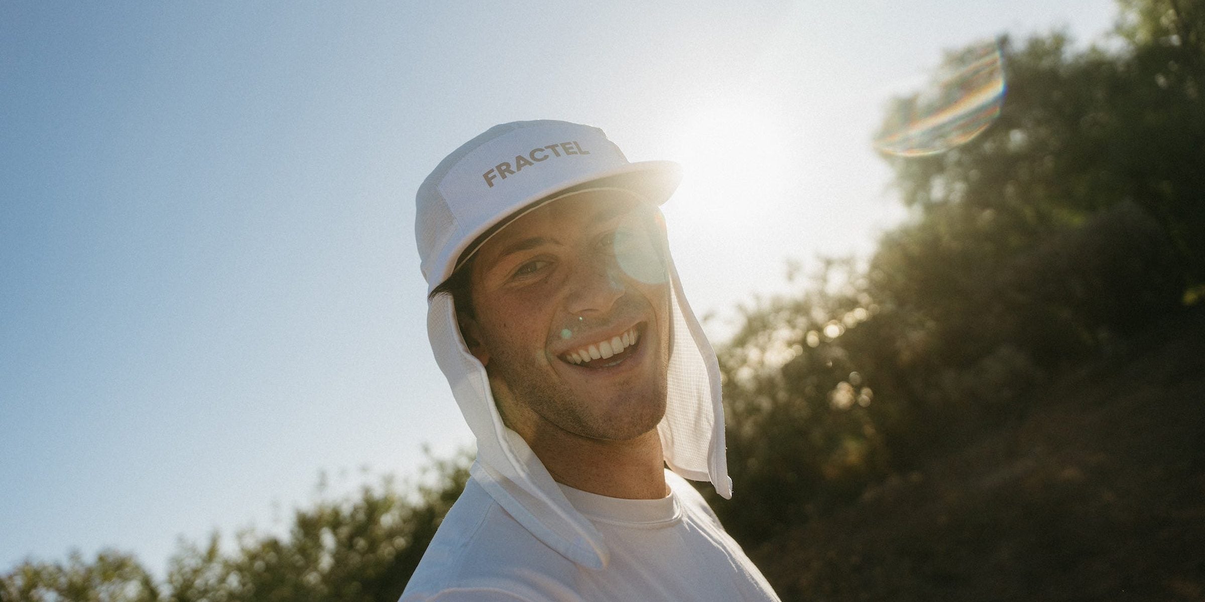 Smiling runner in a white Fractel legionnaire running hat with a neck cape in low sun