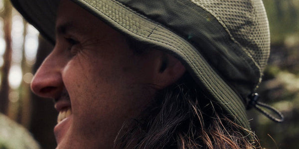 Close-up of a smiling runner in an olive Fractel premium bucket hat with a cord toggle