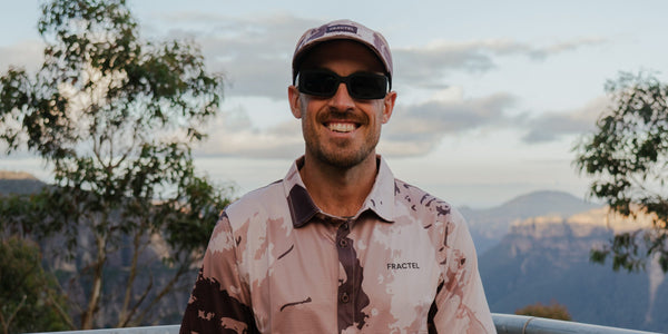 Smiling runner in a Fractel cap and printed collared shirt above the Blue Mountains, Blue Mountains running gear