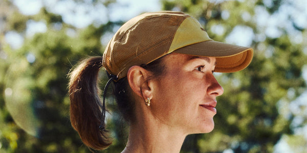 Woman in profile wearing a tan Fractel cap with her ponytail through the back, hats for small heads