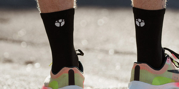 Black Fractel running socks with a white logo and bright running shoes, from the quarter running socks range
