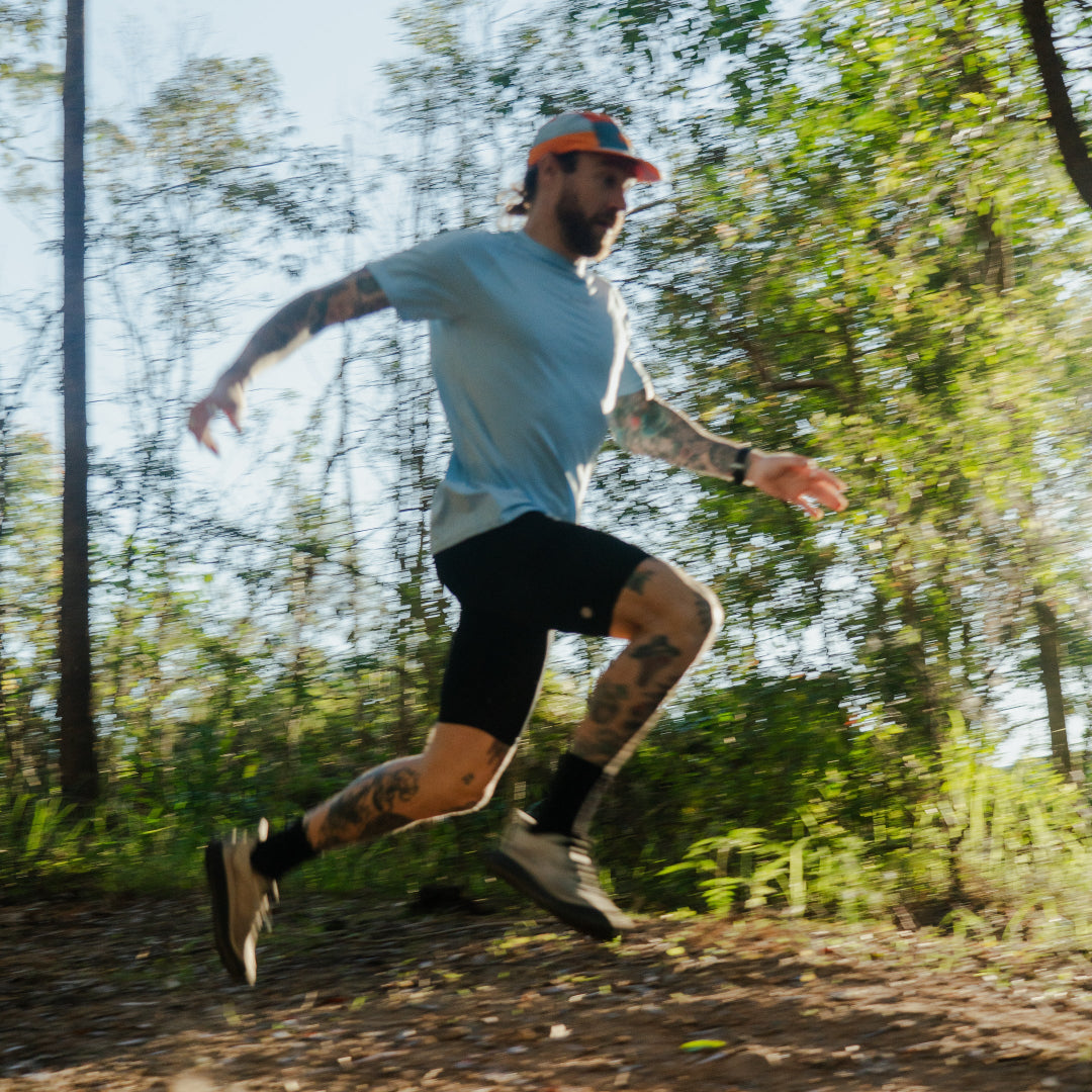 Man running in blue shirt on a trail in a forest