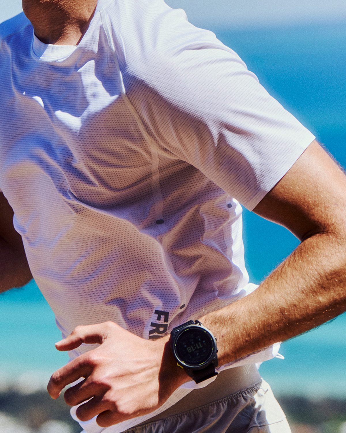 Runner in a white Fractel running t shirt beside the ocean