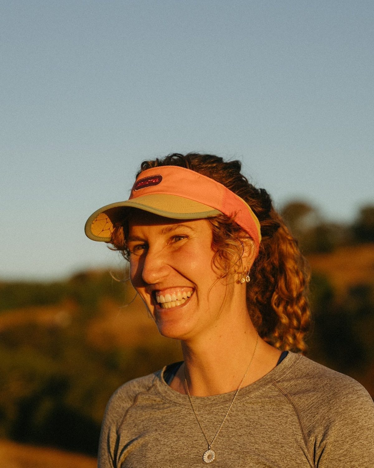 Womens running visor in orange worn by a smiling runner
